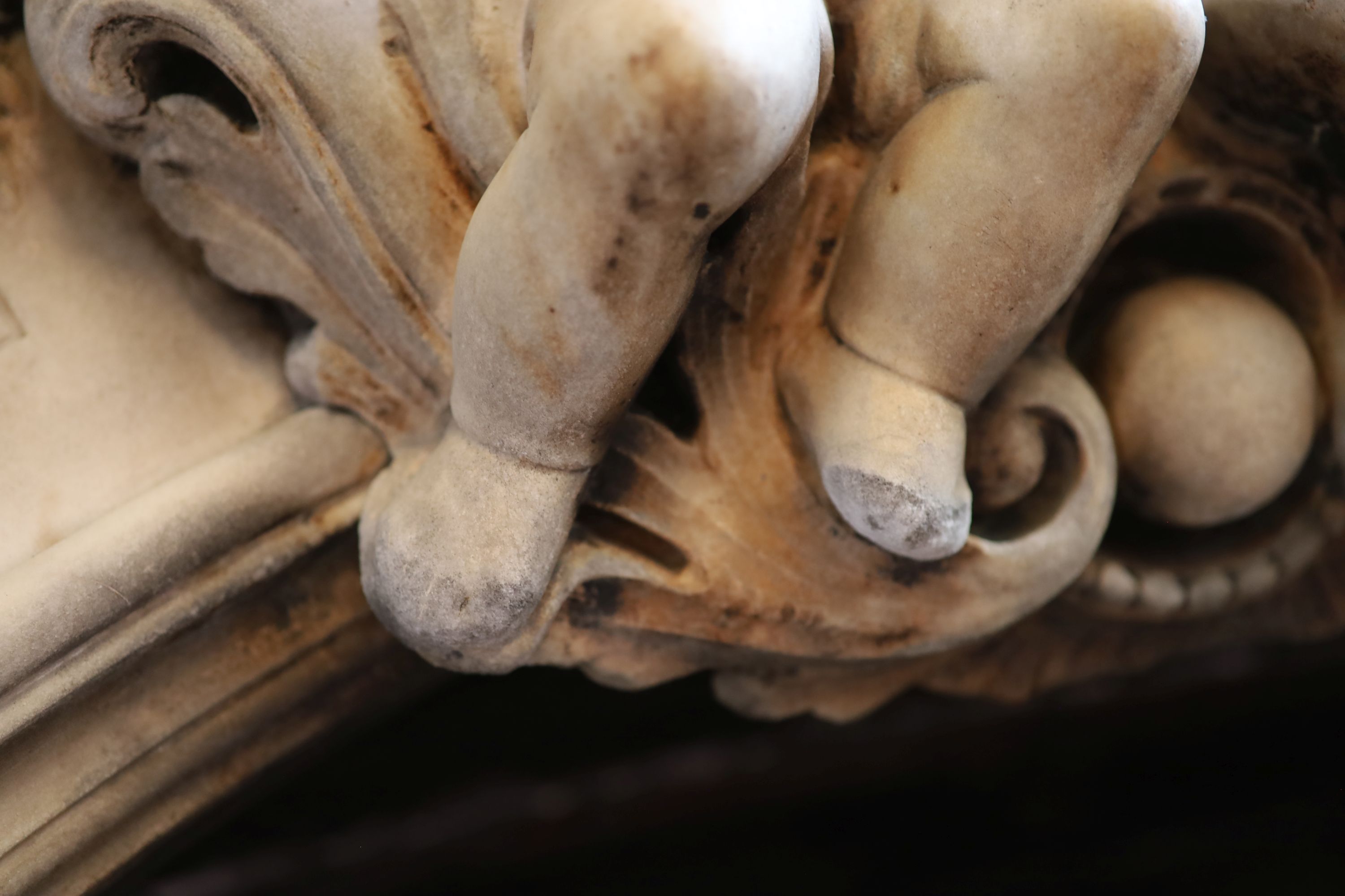 An important mid 19th century Italian white Carrara marble chimney piece, carved in the rococo taste, with seated putti, foliage swags